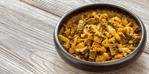 Bitter gourd curry (Karela Sabji in Hindi) with onion, dry mango powder, and spices. Wooden rustic background with space for text.