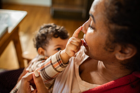 Close up of infant son playfully touching mother nose at home