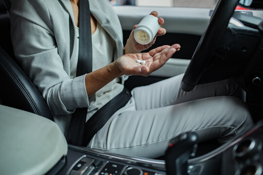 Senior businesswoman taking medication while sitting in a car