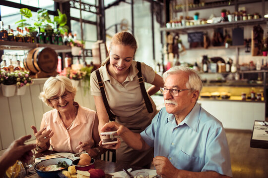 Senior couple paying at restaurant with waitress smiling