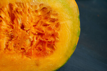 A fresh, juicy slice of pumpkin displayed on a clean grey background, showcasing its vibrant orange flesh and rich texture.