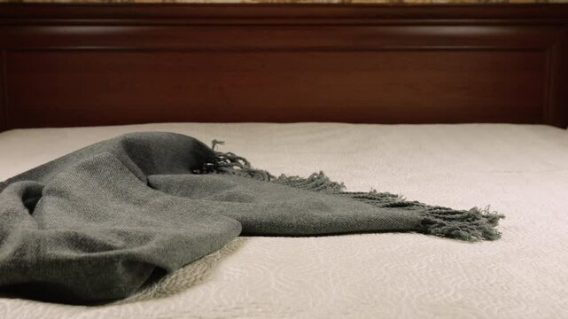 Warm knitted clothes, scarves, hats and sweaters are thrown on the bed.