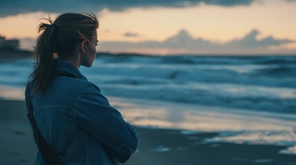 Fototapeta premium Woman Walking on Beach at Dusk Against Ocean Waves