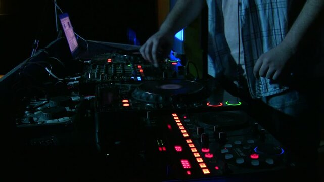 A DJ performing at a club, adjusting the mixer and turntables with vibrant lights illuminating the scene. The focus is on the hands controlling the sound, creating an energetic atmosphere for the crow