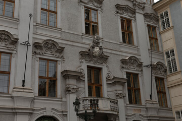 A tall and elegant building featuring a wide balcony with intricate railings and a striking statue majestically perched on its rooftop