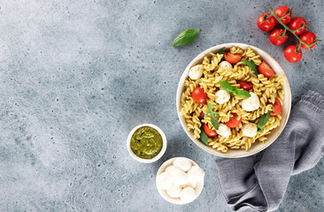 Italian cold salad with fusilli pasta, cherry tomatoes, mozzarella, arugula. Top view. Copy space.