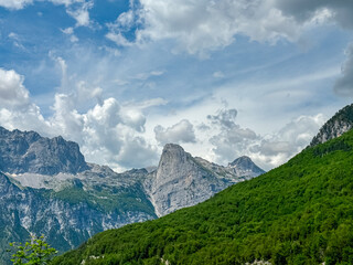 Mountain ridge massif Radohina in Albanian Alps (Accursed Mountains), Northern Albania. Scenic hiking trail from Valbona to Theth. Wanderlust in alpine wilderness. Valley covered by pine tree forest