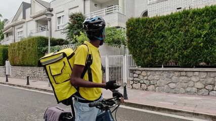 A focused delivery cyclist checks his GPS while holding the handlebars of his bike. Concept of efficient urban food delivery.