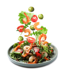 Shrimps and other ingredients falling onto plate on white background