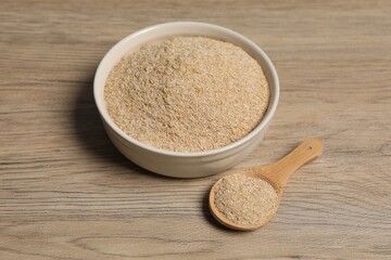 Oat bran in bowl and spoon on wooden table