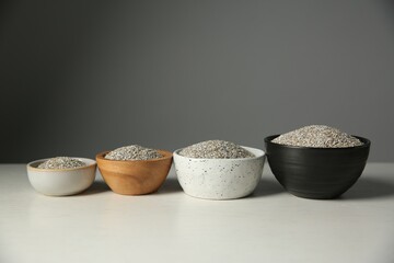 Fresh rye bran in bowls on light wooden table against grey wall