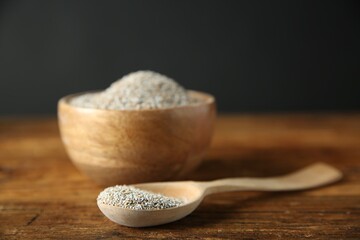 Fresh rye bran in bowl and spoon on wooden table, closeup