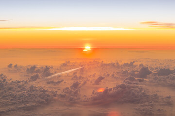 Aerial pilot cockpit view from aircraft, plane of sunrise sunset above the clouds during flight