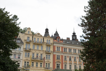 There is a charming row of buildings, each flanked by beautiful trees in front of them, creating a picturesque urban landscape
