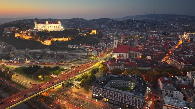 Aerial evening sunset view of Bratislava old town and Bratislava Castle or Bratislavsky Hrad. Cental part of Bratislava with city lights and orange sunset sky, Slovakia