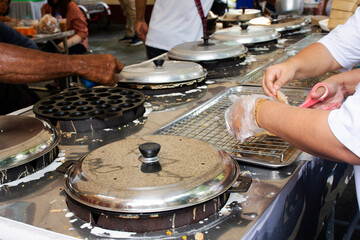 Traditional local thai sweetmeat kanom krok or coconut pancakes pastry pudding cook using rice flour and coconut milk based in almshouse for served guest join Kathin ceremony in Nonthaburi, Thailand