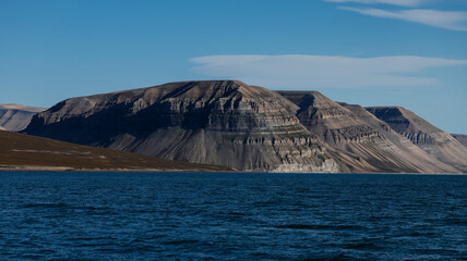Stunning Svalbard landscape showcasing mountains against a tranquil shoreline under a clear sky