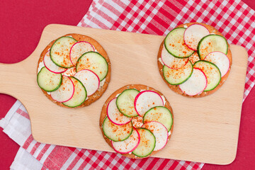 Light Breakfast or Diet Eating - Crispy Cracker Sandwich with Cream Cheese, Fresh Cucumber and Radish on Wooden Cooking Board on Magenta Background