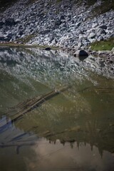 Serene reflection of a rocky coast on a calm lake under a clear sky