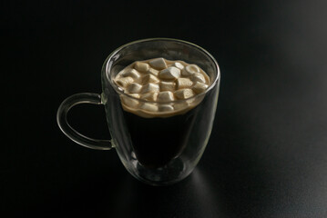 cup of coffee with marshmallow on the black background 