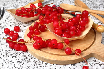 Red currants in bunch on a round wooden cutting board.