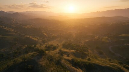 Fototapeta premium A stunning aerial view of a valley and rolling hills at sunset, with the golden light illuminating the landscape.