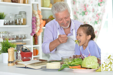 An elderly man and his granddaughter prepare healthy meal