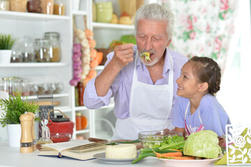 An elderly man and his granddaughter prepare healthy meal