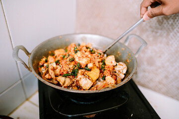 A pan-cooked dish featuring tofu, eggs, chilies, and vegetables.