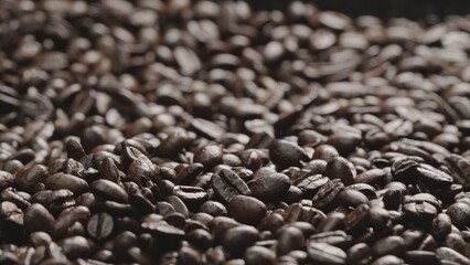 Macro shot of super slow motion shot of fresh coffee bean placed with black background. Close up of piles of aromatic roasted coffee seed surrounded. Macrography. Beans scattering around. Comestible.