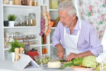 Elderly man in apron preparing healthy food at home