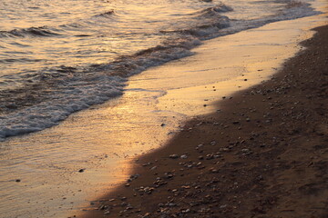 Sunset casts a warm, golden glow on the sea and sand