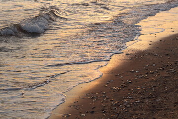 Sunset casts a warm, golden glow on the sea and sand