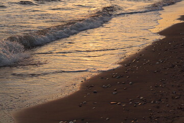 Sunset casts a warm, golden glow on the sea and sand