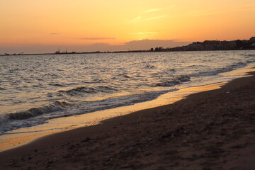 Sunset casts a warm, golden glow on the sea and sand