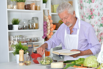 Elderly man in apron preparing healthy food at home