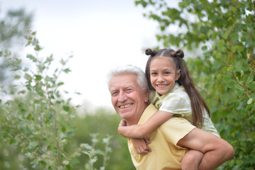 Fototapeta premium Portrait of a little girl with her grandfather in nature