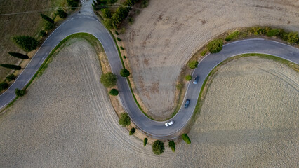 Winding road through golden fields in the heart of Tuscany, Italy at sunset
