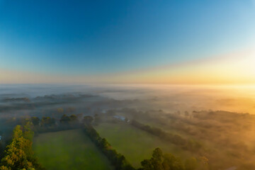 Obraz premium Aerial view of Southeastern Texas in a fog inversion with Autumn colored trees and a deep blue sky.