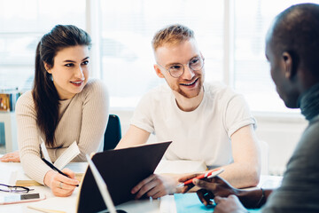 Enthusiastic multiracial students doing research together in library