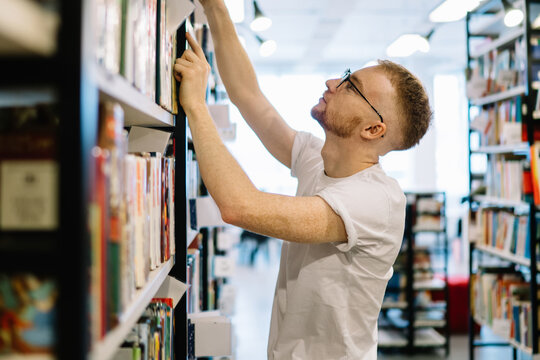 Student taking book from bookshelf in library