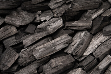 New, black coals, arranged in a neat bed, without embers. The pieces are lined up, ready to light, with a rough texture and dark hue