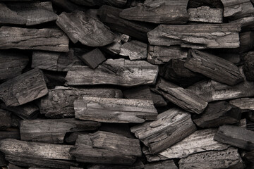 New, black coals, arranged in a neat bed, without embers. The pieces are lined up, ready to light, with a rough texture and dark hue