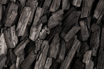 New, black coals, arranged in a neat bed, without embers. The pieces are lined up, ready to light, with a rough texture and dark hue
