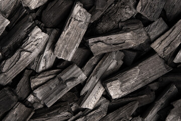 New, black coals, arranged in a neat bed, without embers. The pieces are lined up, ready to light, with a rough texture and dark hue