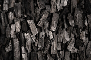 New, black coals, arranged in a neat bed, without embers. The pieces are lined up, ready to light, with a rough texture and dark hue