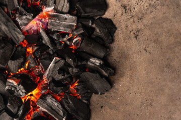 Hot coals with vibrant red and orange hues, emitting intense heat. Glowing pieces surrounded by dark ash, creating a rustic atmosphere