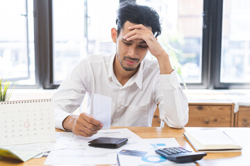 Financial concept, owe asian young man sitting suffer, stressed and confused by calculate expense from invoice credit card bill, no money to pay mortgage or loan. Debt, bankrupt or bankrupt people.