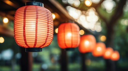 Fototapeta premium A line of glowing red paper lanterns hanging outdoors, creating a warm and festive atmosphere in a peaceful evening setting.
