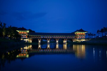 Beautifully illuminated pagoda at night by the river, reflecting its lights on the water